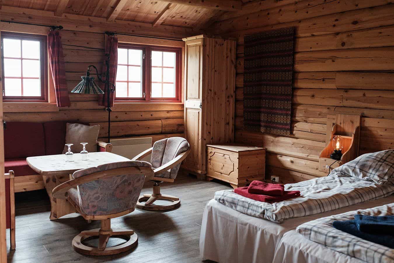 Cozy log cabin room with twin beds, wooden furniture, and two windows at Spiterstulen Lodge