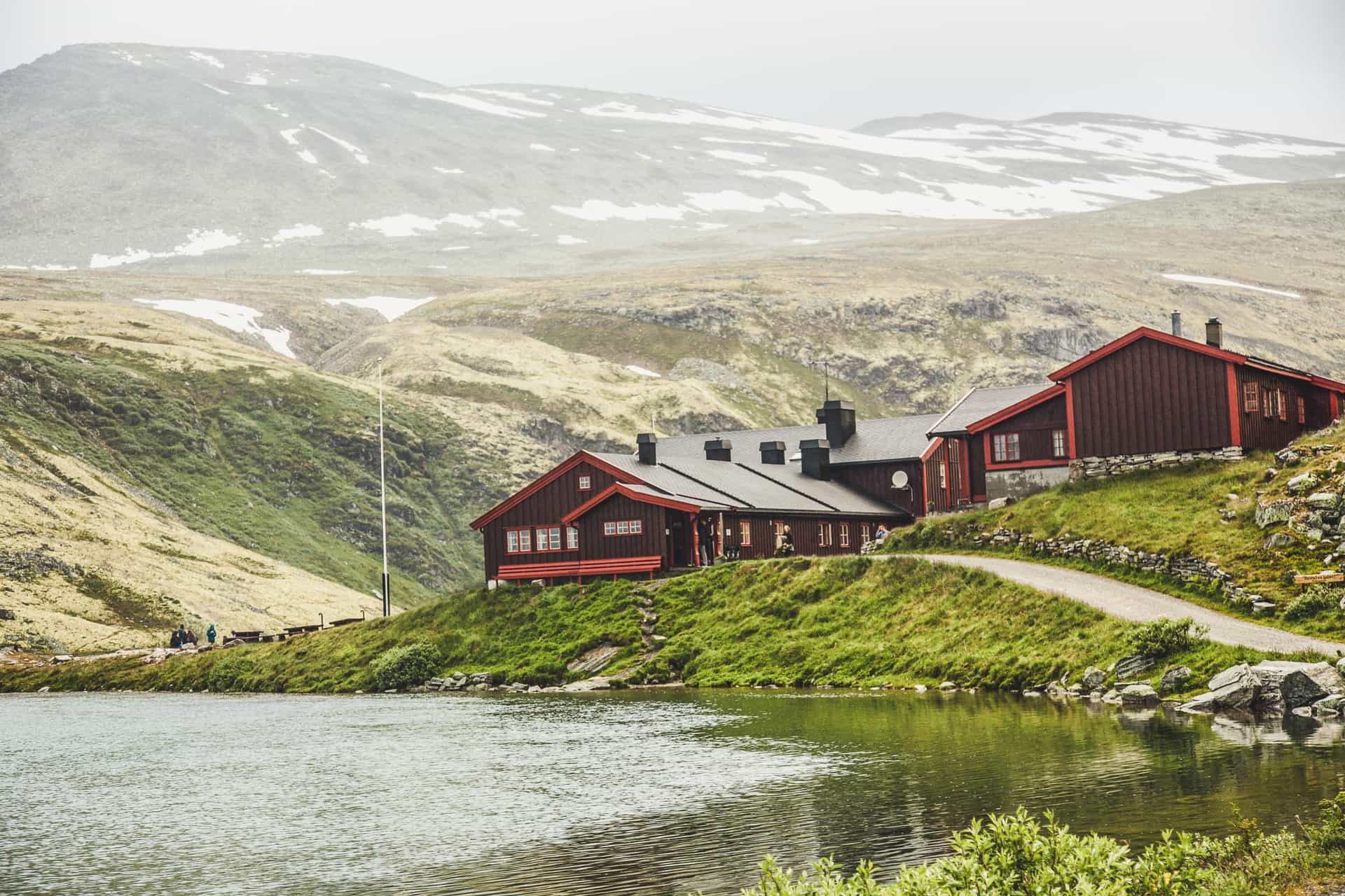 Rondvassbu mountain lodge by lake with snow-dusted peaks in background