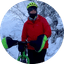 Person with fat bike wearing helmet and red jacket in snowy forest setting