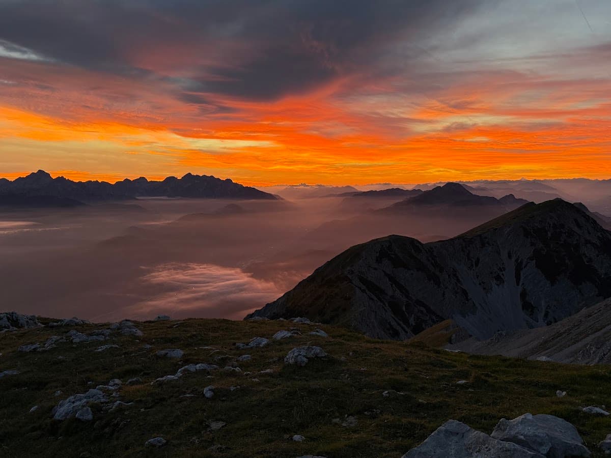 Mountain peaks above sea of fog at sunrise with vibrant orange sky
