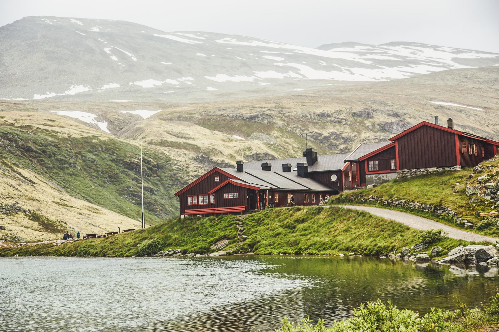 Rondvassbu mountain lodge by lake with snow-dusted peaks in background