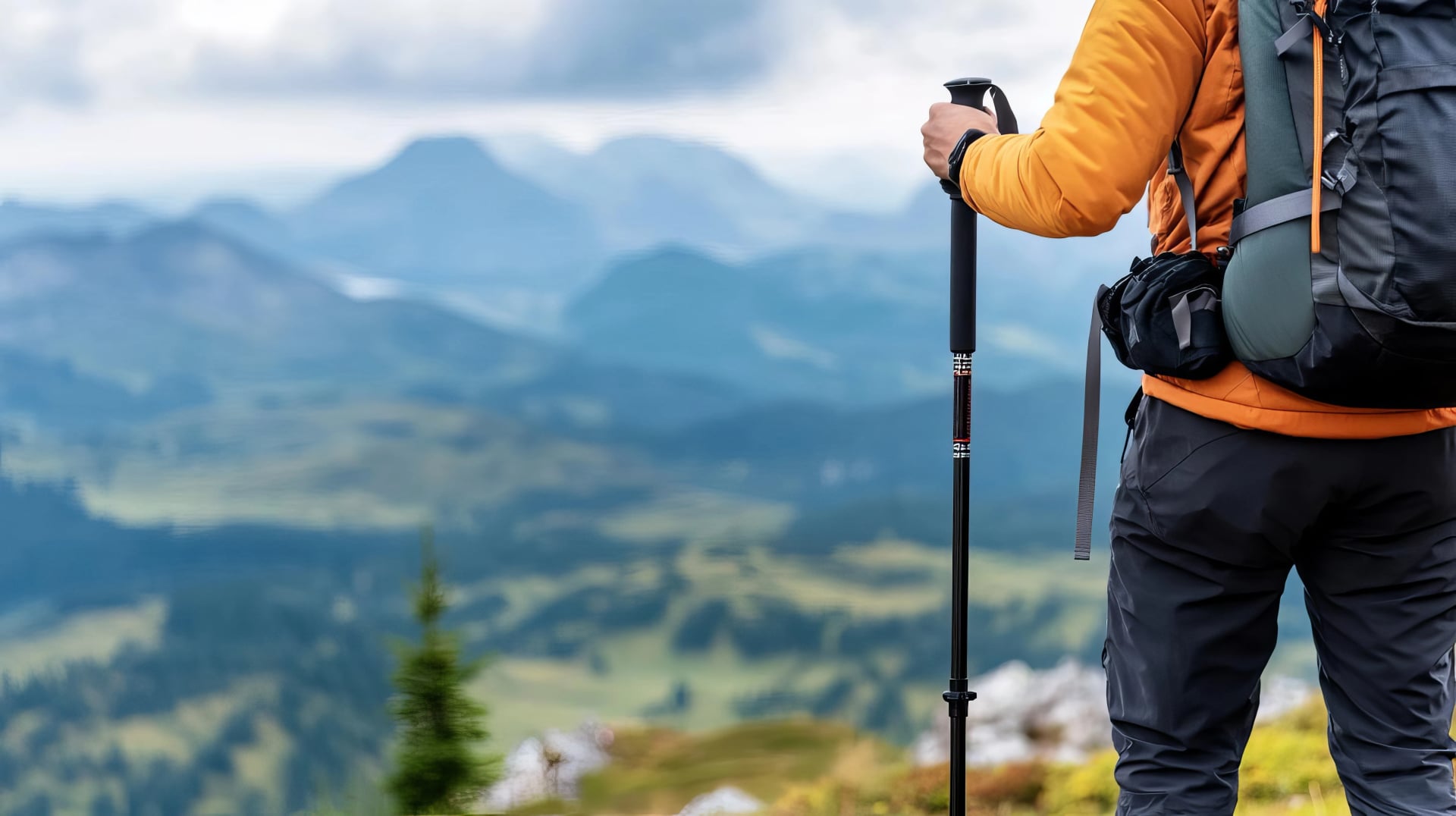 Backpacker adjusting trekking poles, mountain vista in the background, hiking trail gear, support on tough terrain