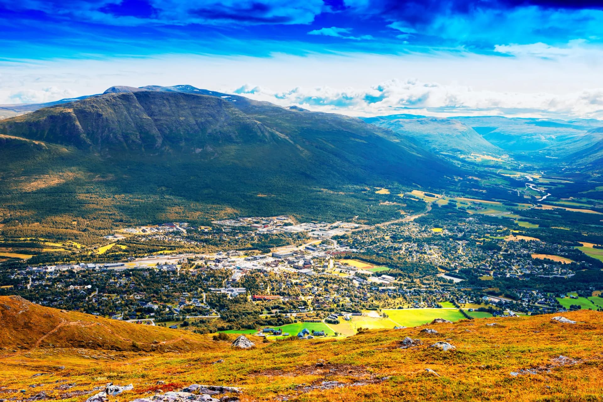 Aerial view of Oppdal town nestled in a mountain valley with autumn colored foreground.