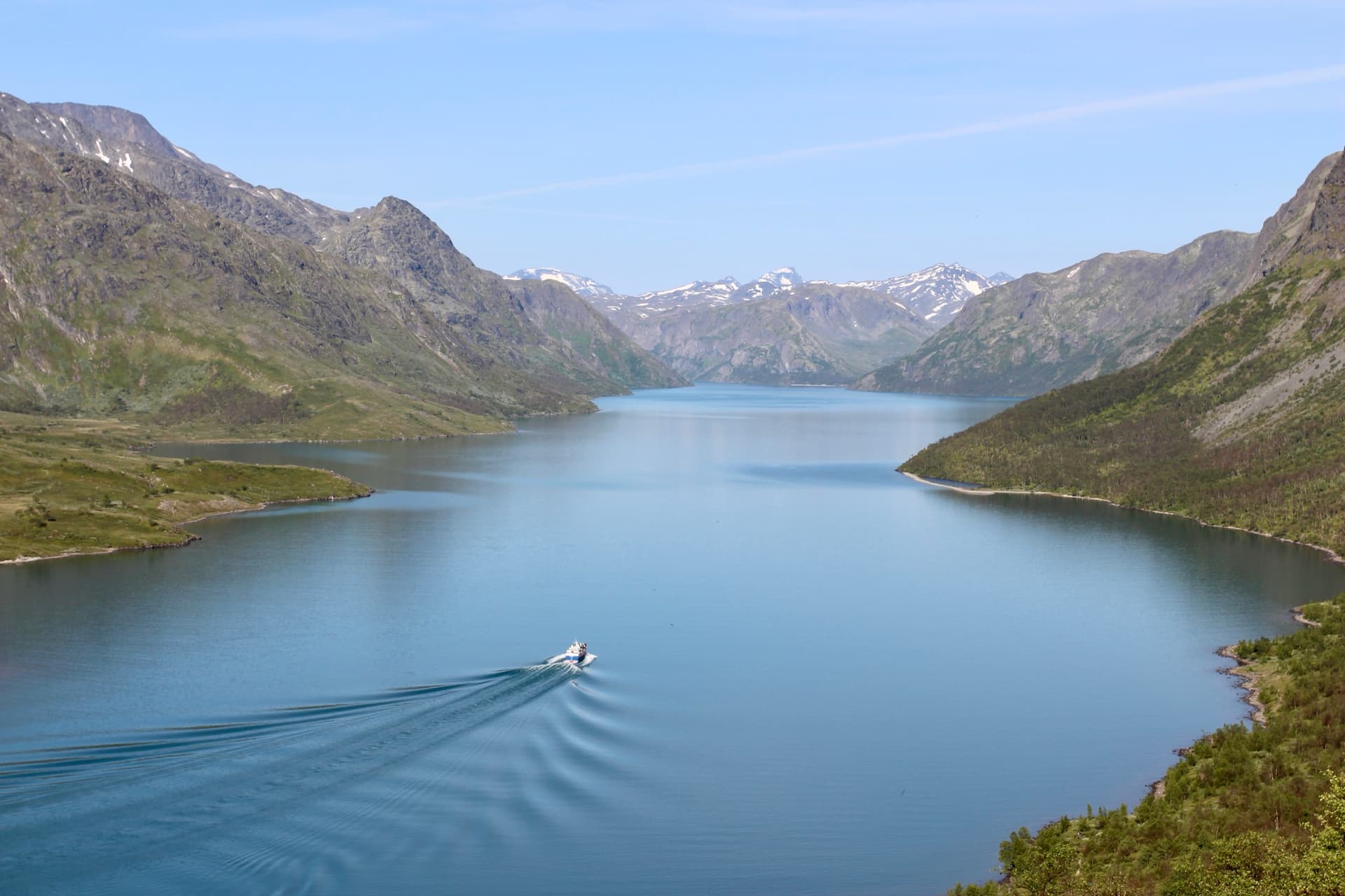 Ferry boat crossing Gjende lake surrounded by mountains in Norway