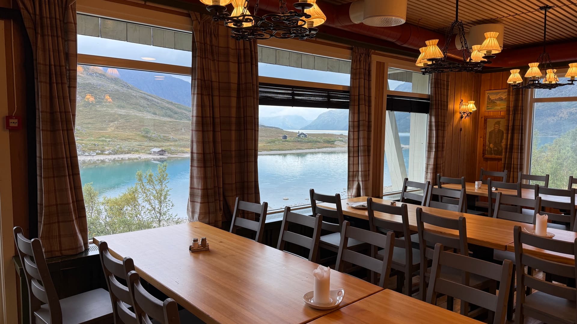 Wooden dining room with large windows overlooking a lake and mountains