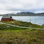 Ein einsames Haus an einem See im Hardangervidda-Nationalpark bei Finse, Norwegen. Das Foto wurde aus dem Zug Oslo-Bergen aufgenommen, einer der spektakulärsten Eisenbahnstrecken Europas.